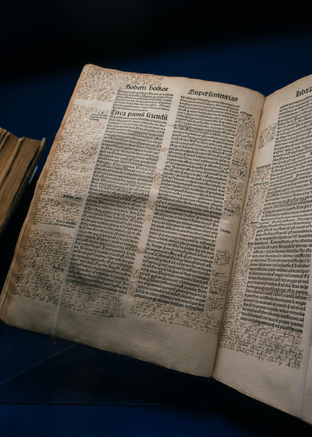 Libro antico con appunti scritti a mano appoggiato su una superficie blu.