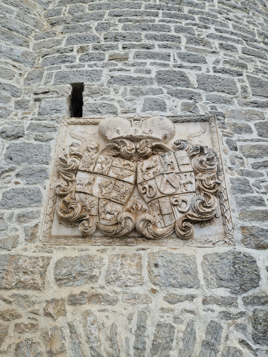 Stemma in pietra finemente scolpito su un muro grezzo.