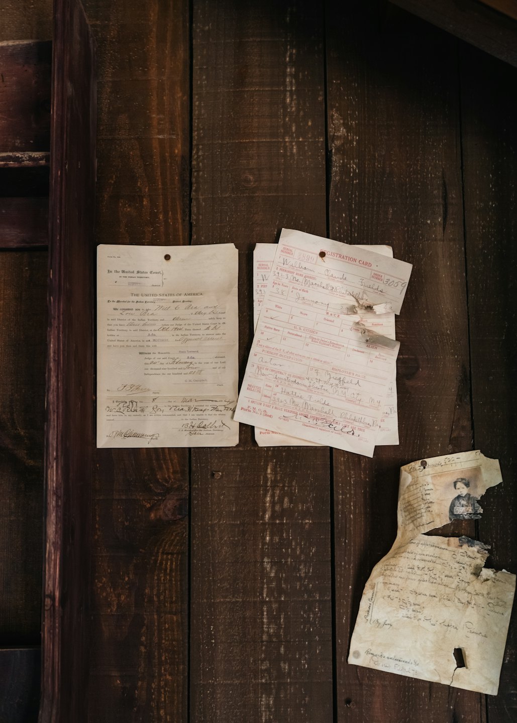Documenti d'epoca appuntati a un muro di legno rustico.
