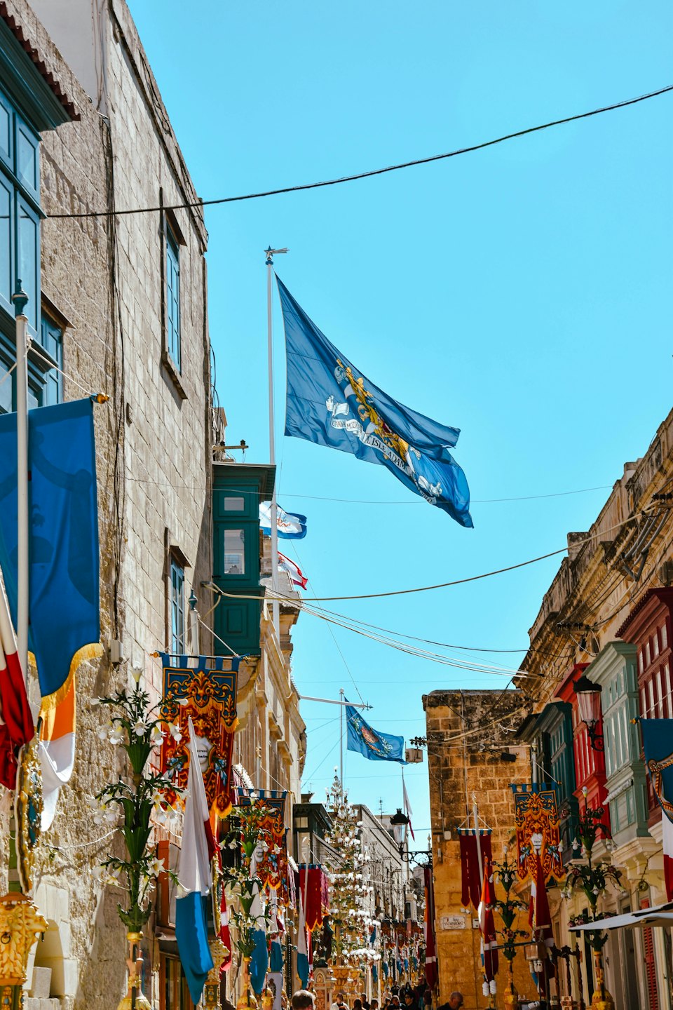 Striscioni e bandiere decorano una strada storica con balconi tradizionali in legno.