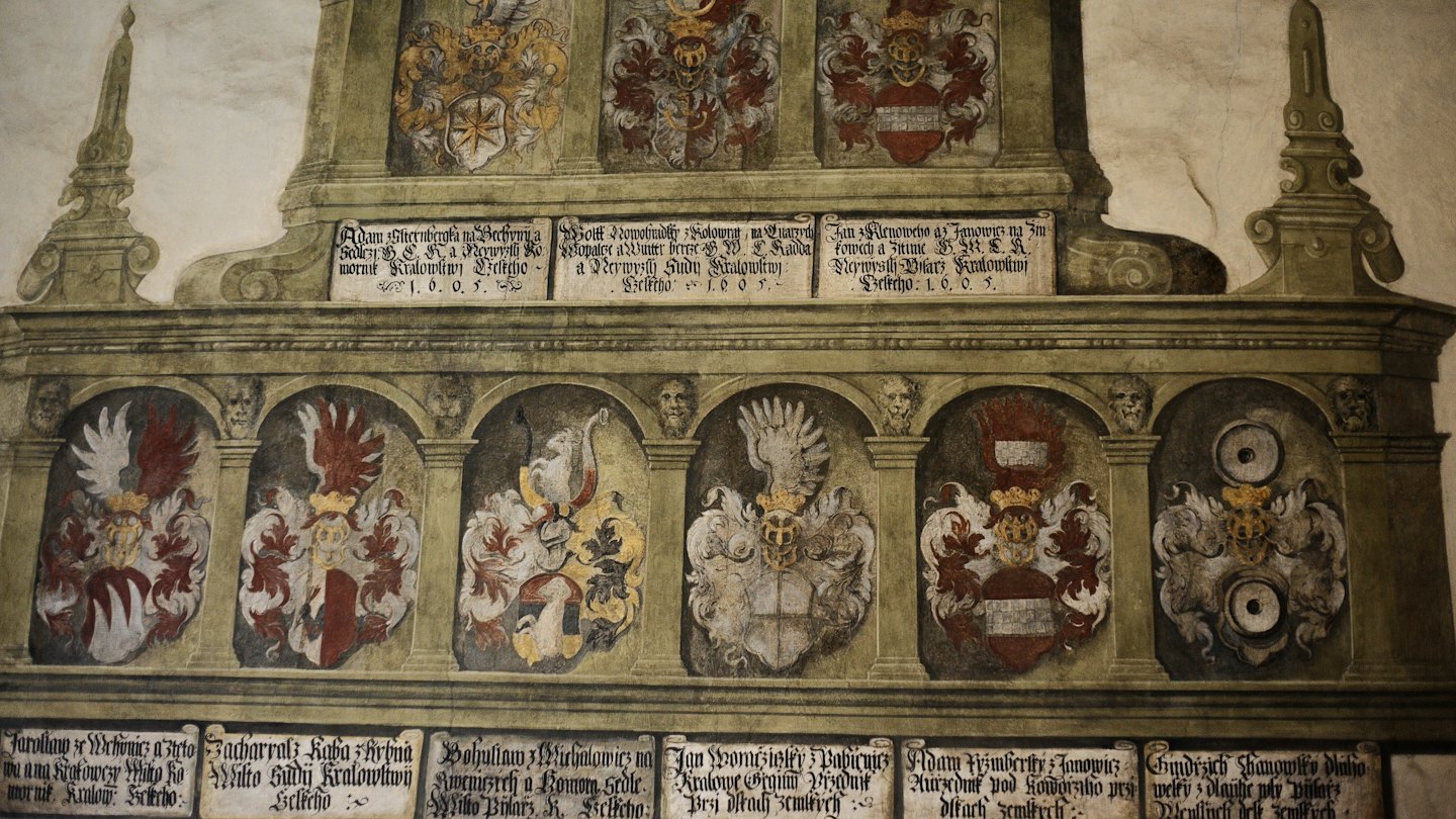 Antico murale con stemmi araldici e testo storico.