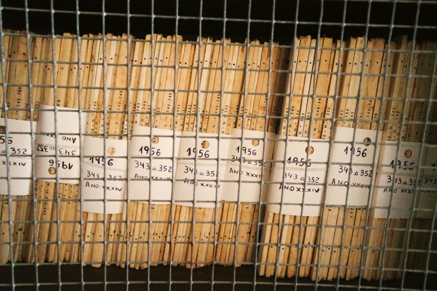 Vecchi documenti d'archivio conservati verticalmente in una rastrelliera metallica.